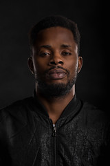 Portrait of handsome young African man on black background