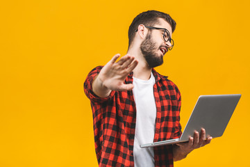 Young caucasian man using computer laptop over isolated against yellow background with open hand doing stop sign with serious and confident expression, defense gesture.