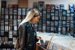 © Akaberka - Young attractive woman choosing vinyl record in music record shop.