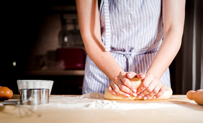 Woman's hands knead dough on a table