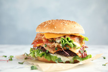Tasty Burger With Bacon On Table Against Color Background