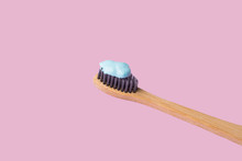 Bamboo Toothbrush With Blue Toothpaste Isolated On Pink Lilac Background. Personal Dental Hygiene Concept. Zero Waste