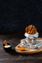 Wall Mural - Baked potato fries with addition sea salt and pepper on a black background, side view, copy space