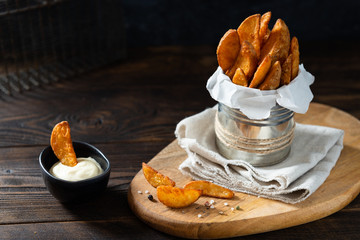 Wall Mural - Hot Fried potatoes in a rustic style, with sauce and spices. In rustic metallic jar, on a wooden table, close view copy space