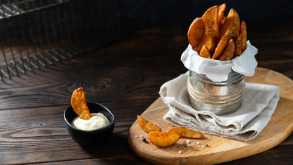 Wall Mural - Baked potato wedges with addition sea salt and pepper on a black background, side view, close up, copy space