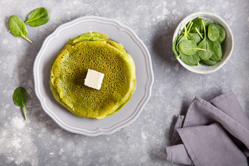 Wall Mural - Spinach pancakes on gray plate.  Stack of green crepes on concrete background. Top view.