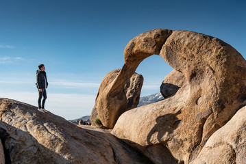 Asian man tourist looking through the mobius arch stone at Alabama Hills, Lone pine, USA. Travel natural attraction concept