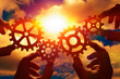© gerasimov174 - Gears in the hands of people against the cloudy sky. mechanism, interaction, team work.