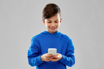 Wall Mural - childhood, technology and people concept - smiling boy in blue hoodie over grey background