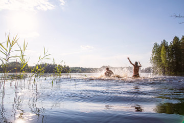 A man and a woman bathe and have fun in a clean, forest lake, on a hot, summer day. Active tourist life.