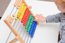 Child Learning To Count. Young Boy Using An Abacus To Learn Maths