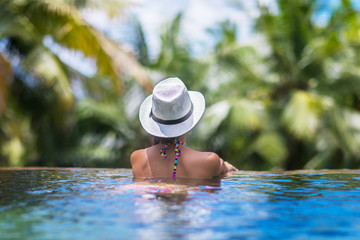 Wall Mural - Young slim brunette woman sunbathe in tropical swimming pool