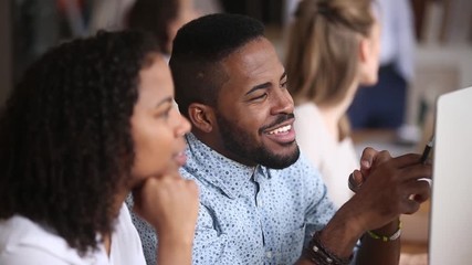 Wall Mural - Smiling male african employee listening female colleague sitting in office