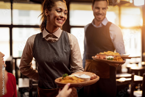Cuadros en Lienzo Happy waiters serving food to their guests in a restaurant.