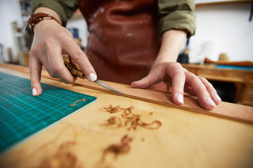 Wall Mural - Closeup of unrecognizable female artisan working with leather standing at table, copy space