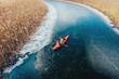 © teksomolika - two athletic man floats on a red boat in river