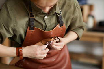 Wall Mural - Mid section portrait of woman artisan making leather belt in leatherworking shop , copy space