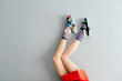 Beautiful female legs in mismatched trendy socks posing in two different fashionable high wedge leather sandals on gray background. Odd disargonized  young girl wearing high sole summer stylish shoes.