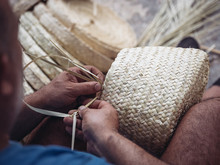 Hands Of Anonymous Artisan Showing Lovely Basket With Floral Ornament Braided From Dried Palm Fiber