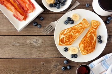 Wall Mural - Tie shaped pancakes with blueberries and bananas. Fathers Day brunch concept. Top view corner border on a rustic wood background.