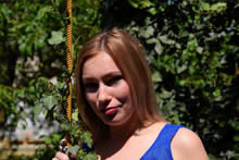 Portrait Of A Girl In A Blue Dress On A Background Of Green Arbor Of Ivy.