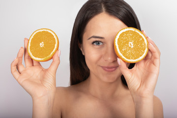 beautiful brunette girl, blue eyes, in her hand an orange, white background, close-up