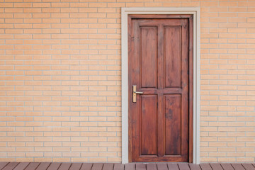 Wall Mural - front view vintage brown wooden door on red brick wall. (selective focus)