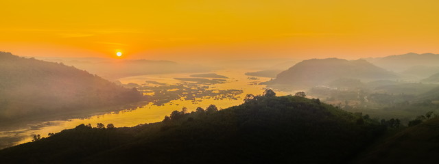 sunrise at Phu Huay E San View Point, view of the hill around with sea of mist above Mekong river with red sun light in the sky background, Ban Muang, Sang Khom District, Nong Khai, Thailand.