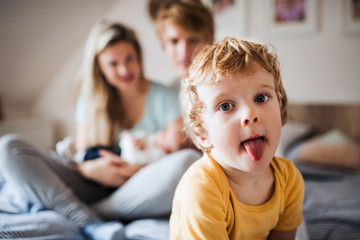 Wall Mural - A small toddler boy with parents and newborn baby at home.