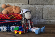 Stack Of Warm Woolen Blankets And Doll On Wooden Background. Childrens Textile Toys. Home Cosiness. Handmade Toy. Colorful Plaids.