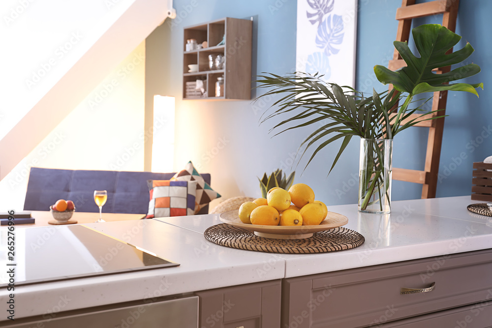Plate with fresh lemons on table in interior of modern kitchen