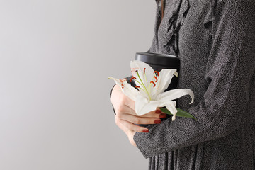 Wall Mural - Woman with mortuary urn and lily flower on light background