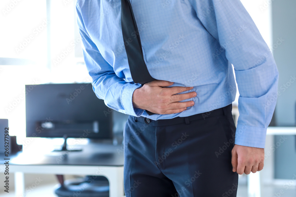 Young man suffering from stomachache in office