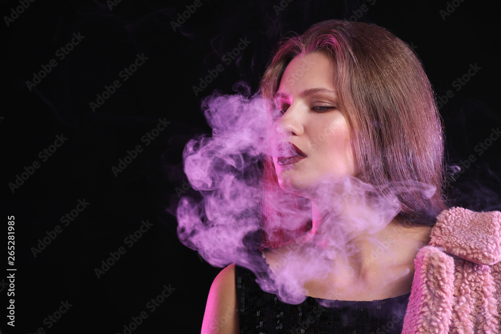 Young woman smoking on dark background