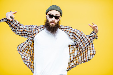 Wall Mural - Portrait of a cool stylish man in shirt and hat posing on the bright yellow background