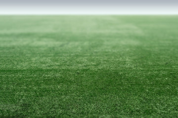 Green sports field with artificial grass, football field perspective.