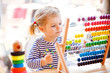 © Irina Schmidt - Adorable cute beautiful little toddler girl playing with educational wooden rainbow toy pyramid and counter abacus. Healthy happy baby learning to count and colors, indoors on sunny day.