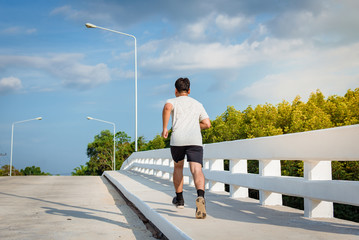 The man with runner on the street at bridge be running for exercise