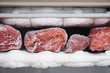 Large pieces of red meat in a freezer with a big quantity of frozen ice and snow