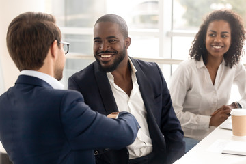 Happy african businessman handshake reliable male partner at team meeting