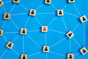 Leadership and network teamwork concepts Red businessman icon on the wooden block in the middle between the black business icon on the wooden blocks.