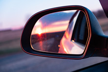 The Reflection Of The Setting Sun In The Rearview Mirror Of The Car