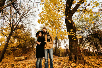 attractive happy luxury couple hugging and holding hands with tender in autumn colorful park