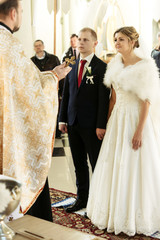 wedding ceremony of happy elegant blonde bride and stylish groom, holding hands in the old church