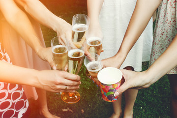 Wall Mural - hands of woman holding colorful glasses and toasting champagne at joyful party in summer park, bridal shower or wedding reception