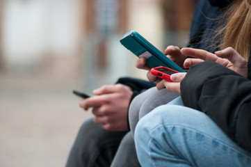 closeup of teenagers surfing on smartphone in the street