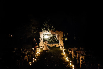 Wall Mural - candle light in glass lanterns and wooden arch and lamp at luxury wedding ceremony in evening, decor and arrangements