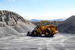 © Designpics - Wide angle view of a large wheel loader heavy equipment machine parked in front of a gravel pile in the mountain landscape; Iceland