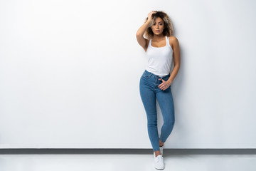 Full length portrait of stylish young black woman standing on white background.