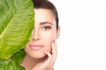 Wall Mural - skin care concept with a young beautiful woman touching her face behind a leaf. spa beauty portrait